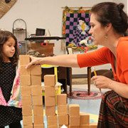 Teacher help student to construct tower using wood block